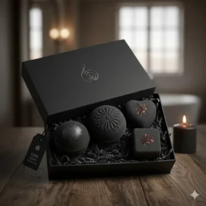 A beautifully packaged gift set featuring several artisanal black bath bombs with various scents and shapes.