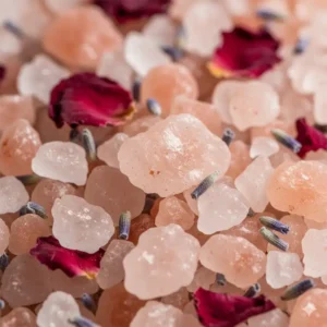 Macro view of coarse pink Himalayan salt crystals mixed with dried flower petals for shower salts aromatherapy.