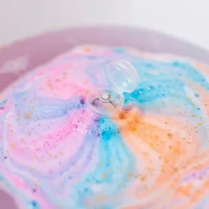 Illustration showing organic ingredients used in skin-safe jewelry bath bombs, featuring shea butter and lavender essential oil drops.